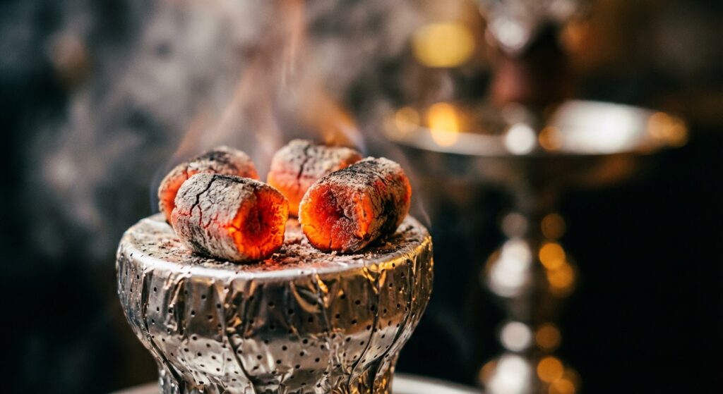 یک کلوزآپ هنری از زغال‌های گداخته که روی سری قلیان با فویل گذاشته شده‌اند. فوکوس روی زغال‌ها باشد و پس‌زمینه مات.